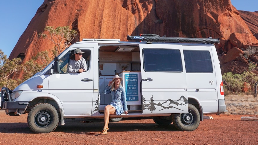 Jamie and Camile from All About Adventure sit in van park in front of Uluru