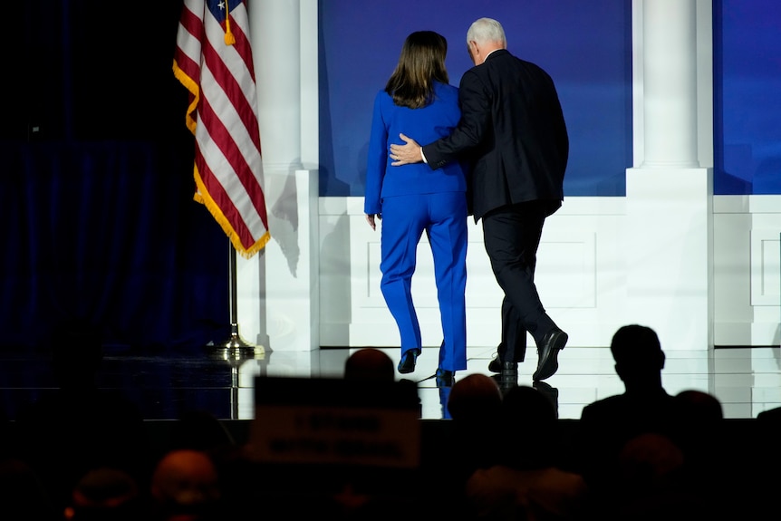 a woman with dark hair and a blue suit and pence in a black suit 