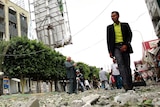 Man walks past damaged buildings in Sana'a
