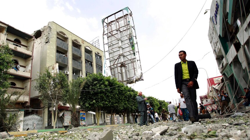 Man walks past damaged buildings in Sana'a
