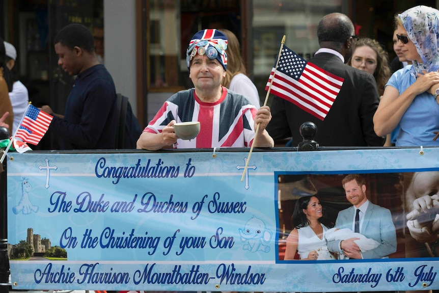 Fans line up in the streets of Windsor with a large sign for Archie's christening