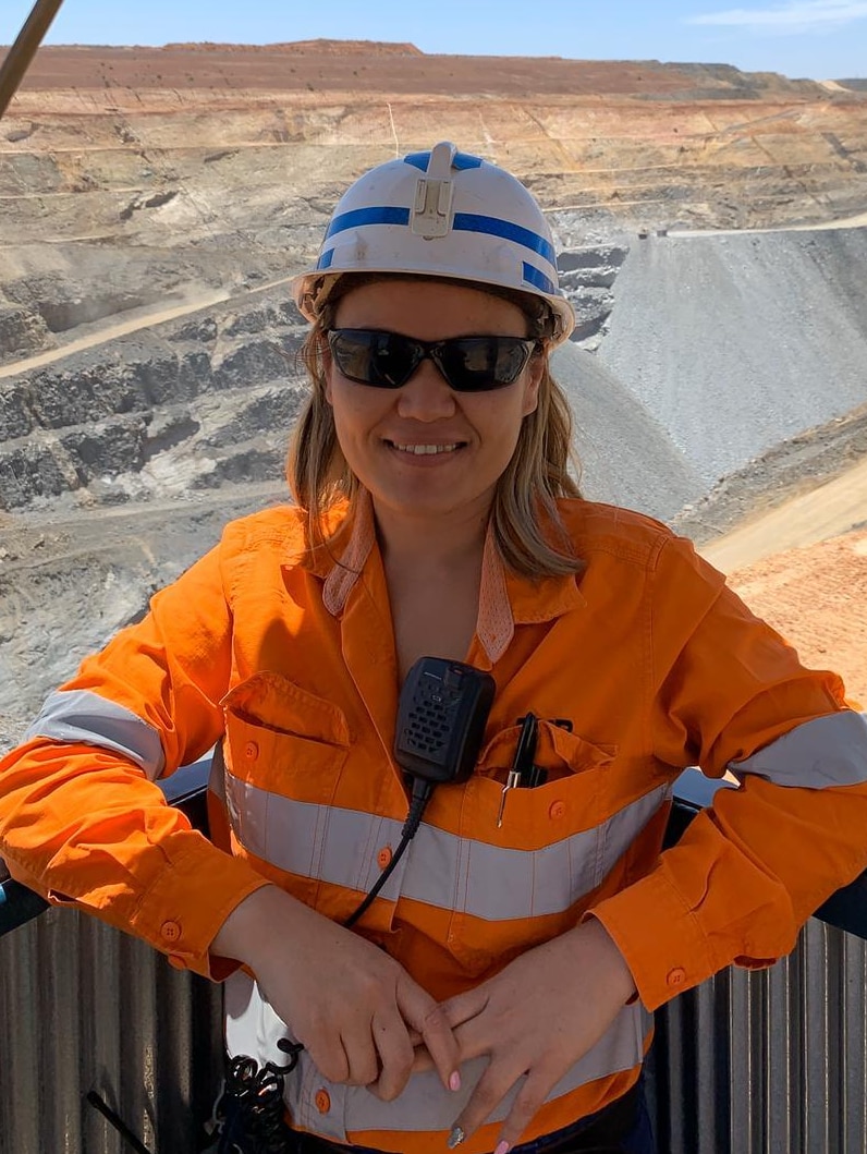 A woman in orange uniform is on a mining site.