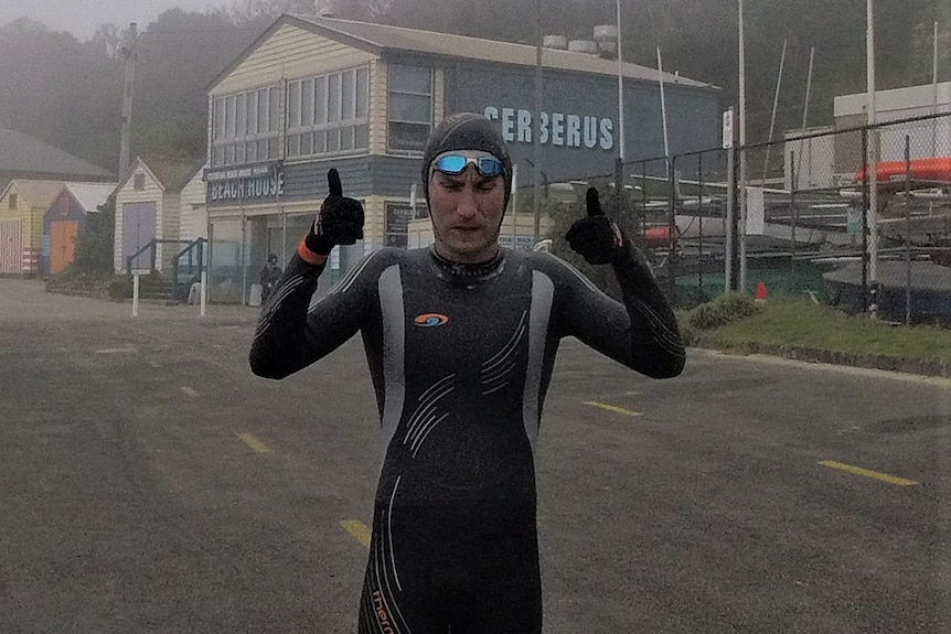 Ben Morrison, in full wetsuit gear, gives a double thumbs up