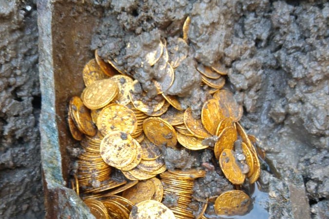 A muddy soapstone jar filled with gold coins