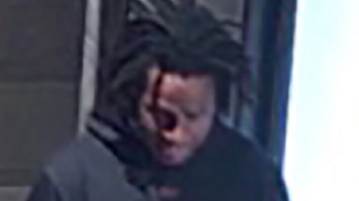 A CCTV still image of a man in a black hoodie with 'PNG' written on the front of it.
