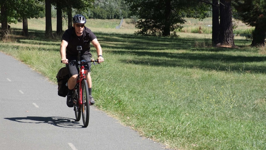 A man riding an E-bike on a Canberra footpath.