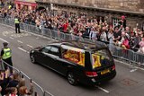 A hearse carrying the coffin of the Queen travels down the Royal Mile.