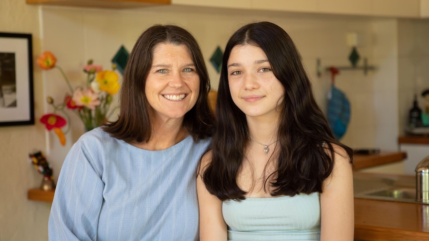 A woman with dark hair smiles with a girl with dark hair 