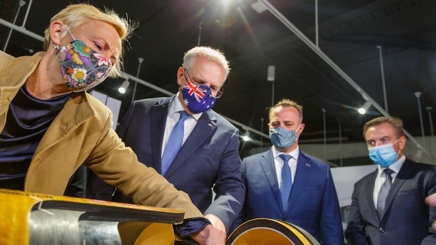 Katie Allen, Scott morrison and Tim Wilson look at an electric vehicle engine prototype