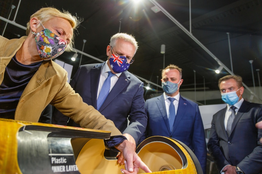 Katie Allen, Scott morrison and Tim Wilson look at an electric vehicle engine prototype