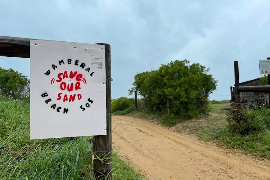 Un panneau à côté d'un chemin de terre.