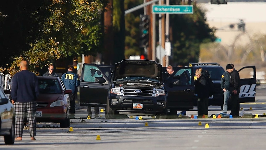 FBI and police continue their investigation around the area of the SUV vehicle where two suspects were shot by police following a mass shooting in San Bernardino
