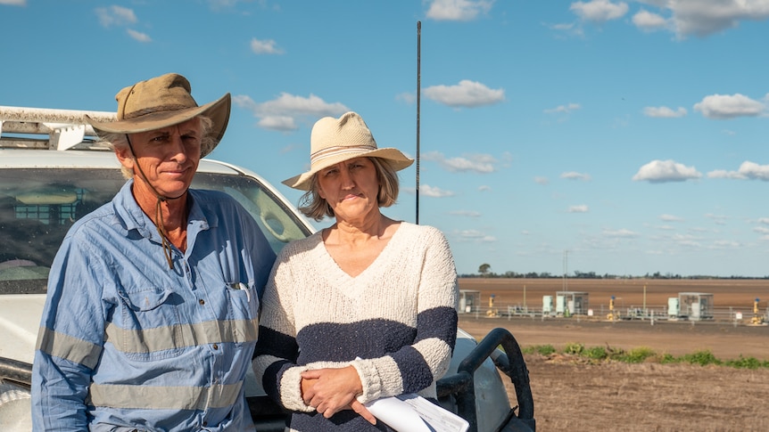 Gary and Zena Ronnfeldt stand near a farm ute with gas wells behind them, Dalby, Queensland, May 2021.