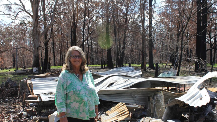 Esther stands in front of a shed which has been destroyed in Dondingalong.