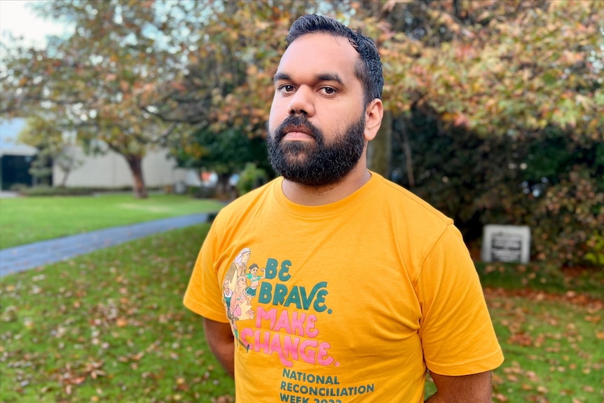 A man in a yellow shirt that reads be brave make change