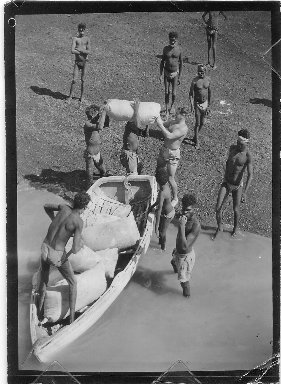 Monochrome of aboriginal people unloading a small boat.