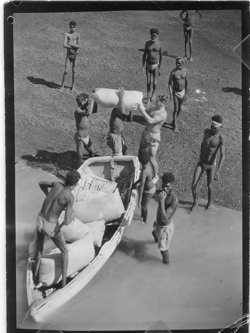 Monochrome of aboriginal people unloading a small boat.