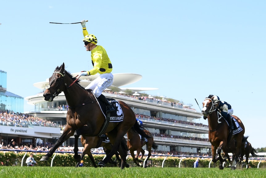 Mark Zahra holds his arm up as Without A Fight runs ahead of other horses