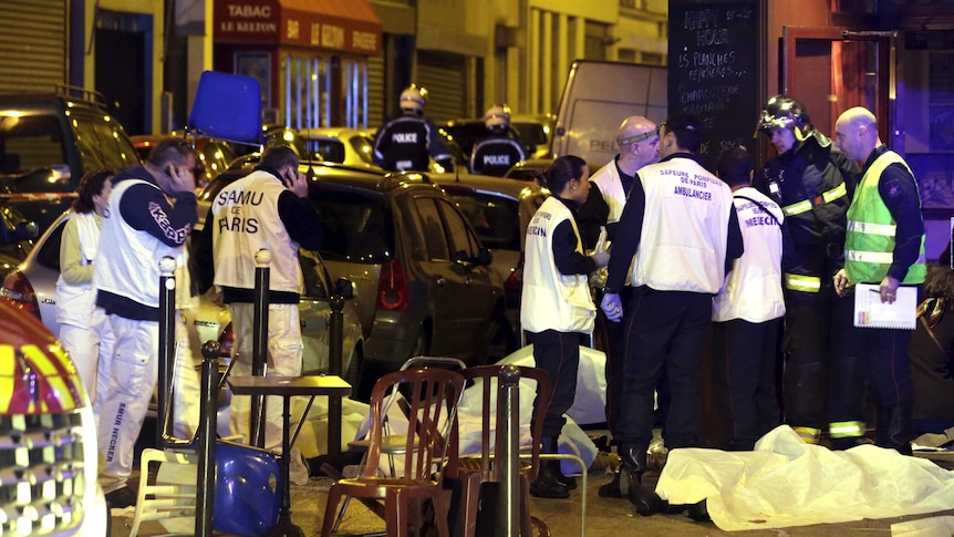 Emergency service personnel work near covered bodies