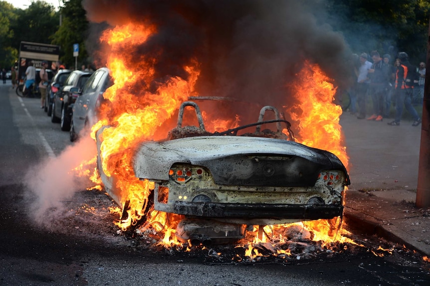 A car on the street is engulfed in flames.