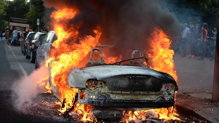 A car is set alight during protests against the G20 summit. (Photo: AP/Christophe Gateau, dpa)