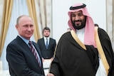 Russian President Vladimir Putin smiles and shakes hands with Mohammed bin Salman during a meeting.