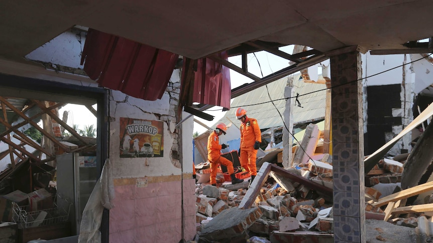 Rescuers climb over rubble