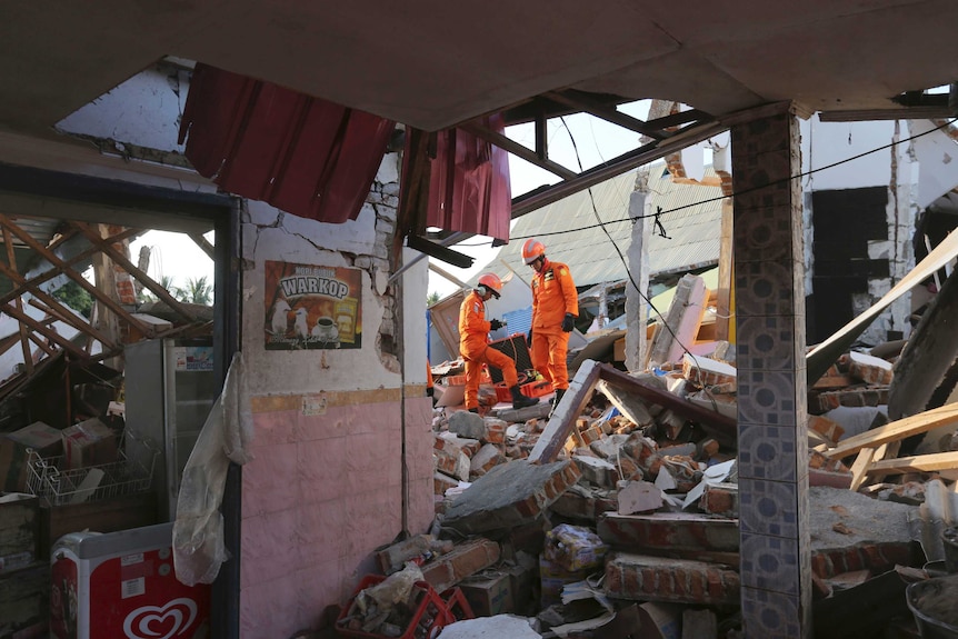 Rescuers climb over rubble