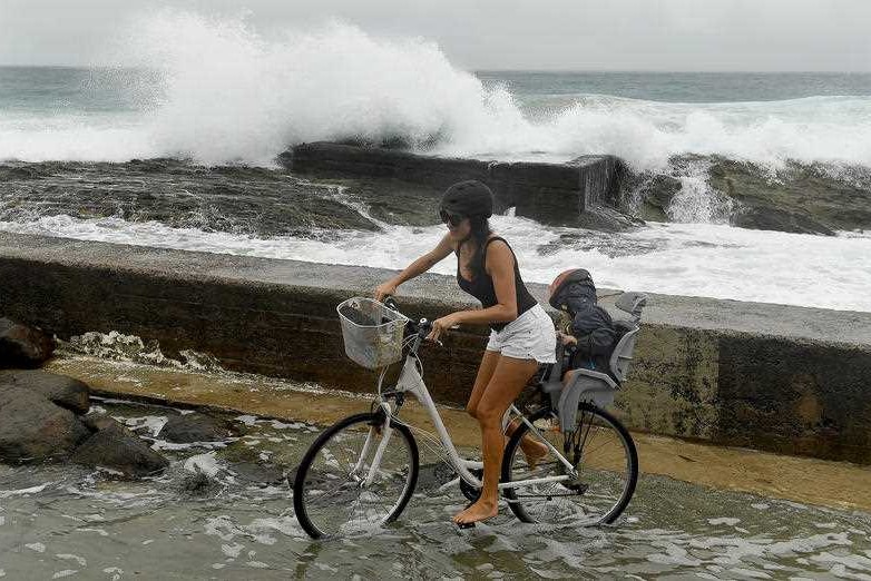 A woman negotiates a flooded path at Snapper Rocks on the Gold Coast.
