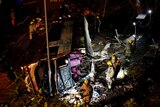 Rescuers inspect a crashed bus by torch light