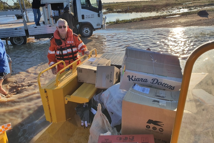 A woman in a boat with lots of boxes surrounded by water.