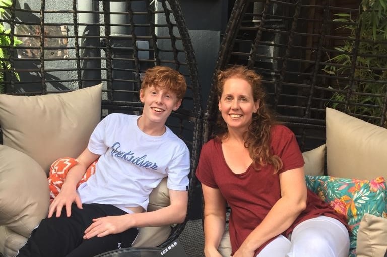 Dan (left) and his mum sitting on black chairs.