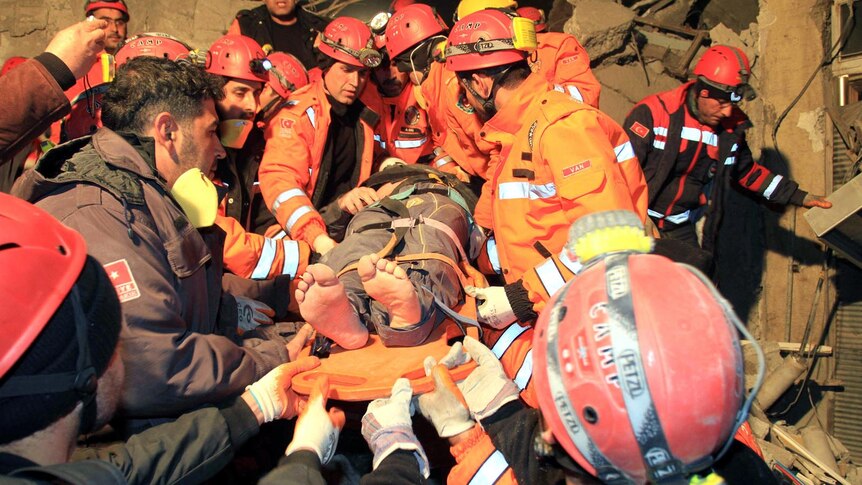 Rescuers carry a survivor from a collapsed building after a magnitude 5.6 earthquake in Van.
