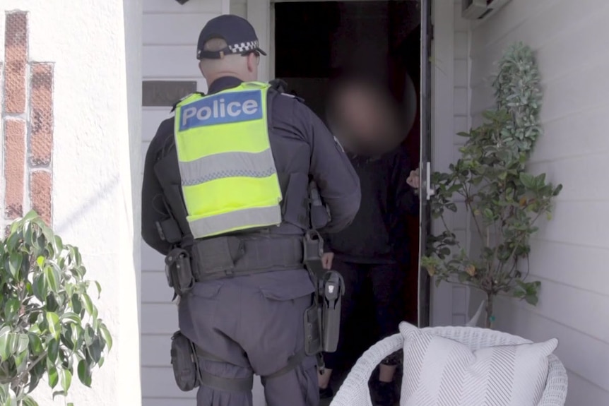 A police officer speaks to an unidentified woman at her front door.