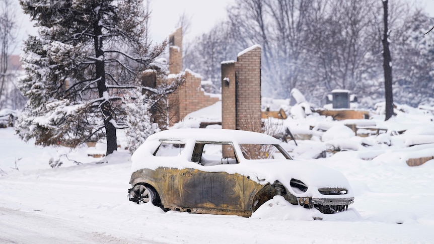 Snow covers a burned out Mini Cooper car in Louisville.