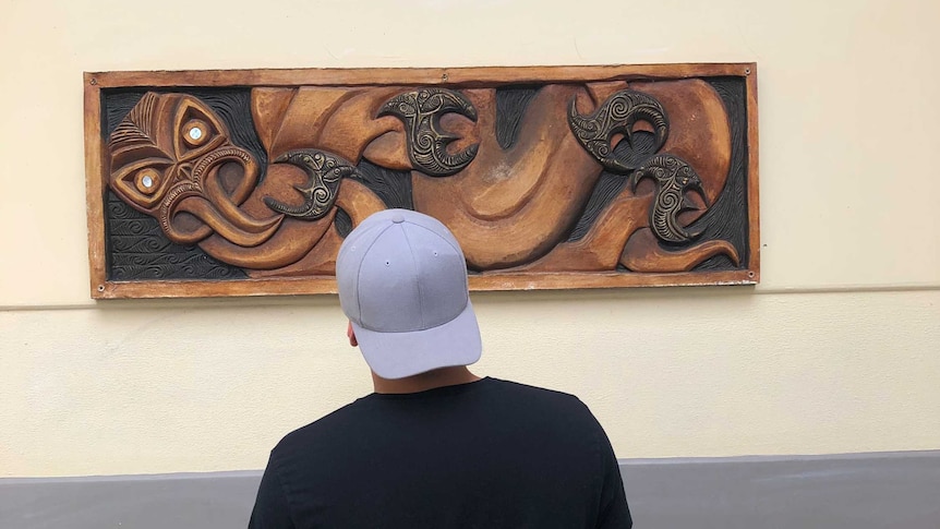 Young man gazes at wall carving