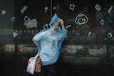 A woman wearing a raincoat walks along a street in Ningbo