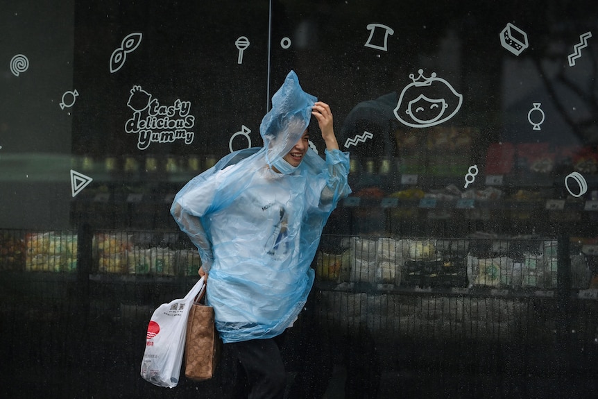 A woman wearing a raincoat walks along a street in Ningbo