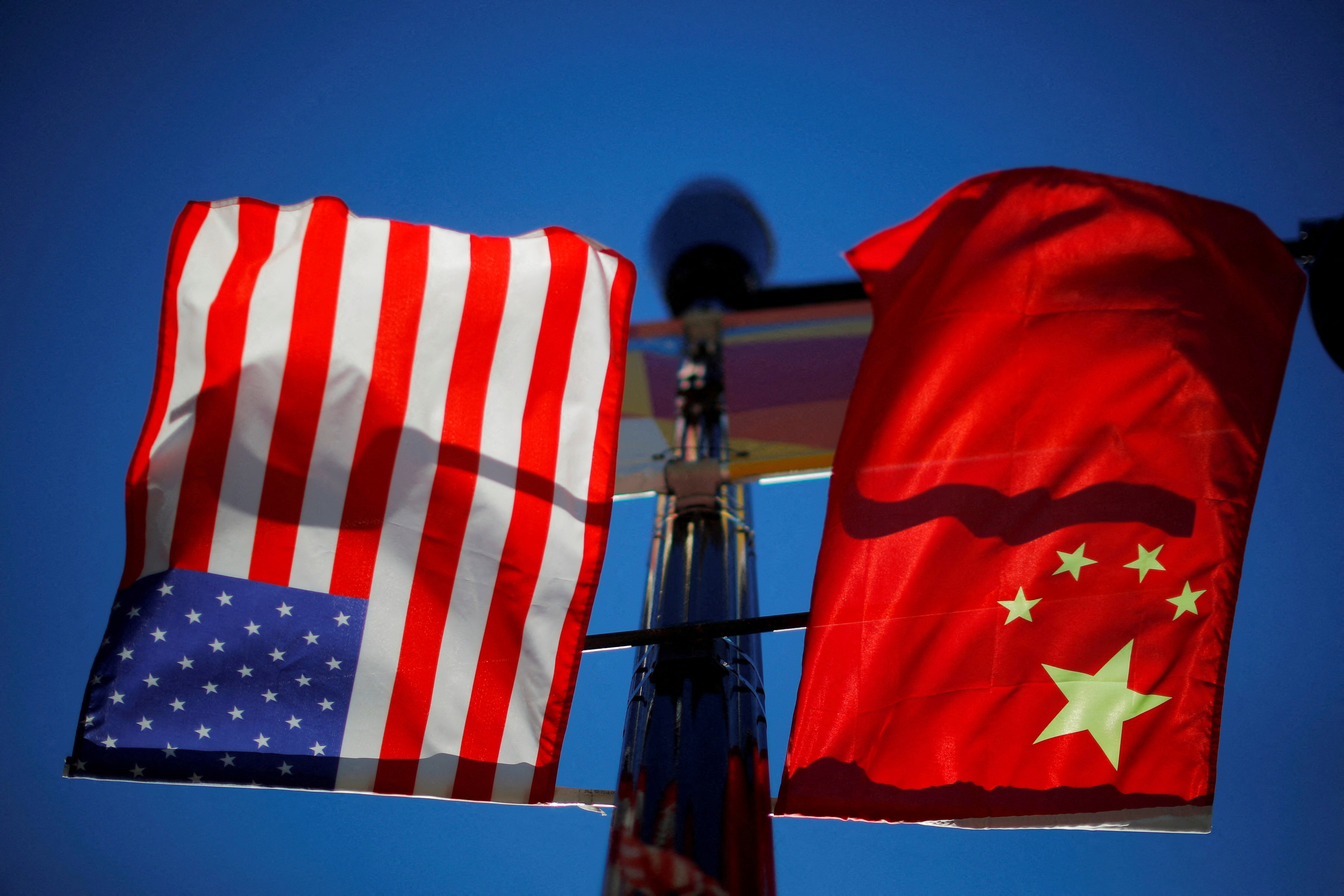 the US and China flags both hang separately but next to each other