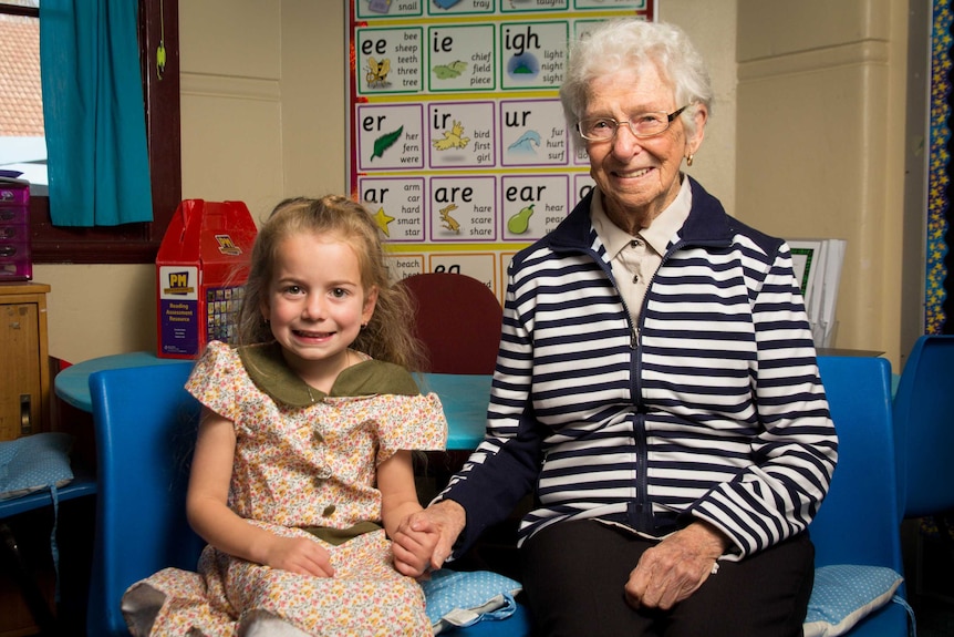 Haddie Whiteside and Peg Veale hold hands in a classroom.