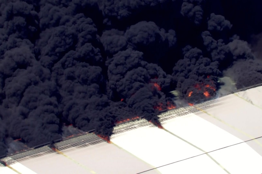 Thick dark smoke billowing from a white roof