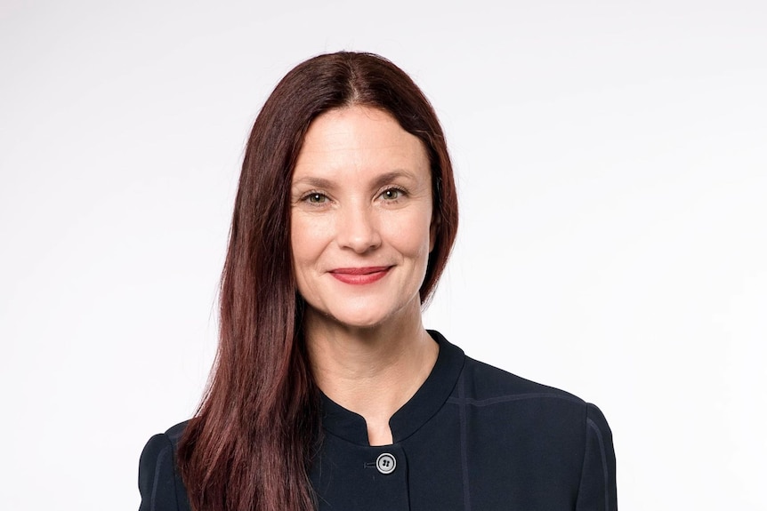 head shot of woman with long red hair in black top