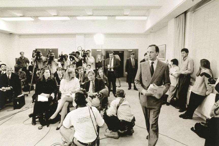 Black and white photo of media sitting in room as Paul Keating walks in.