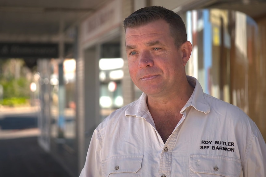 Roy Butler wearing a white shirt standing outside a shopfront. 