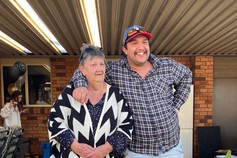 A smiling man has his hand around his grandmother.