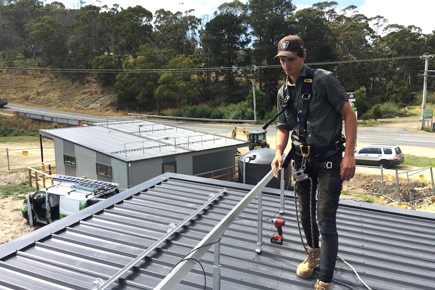 A man installing solar panels on a roof. 