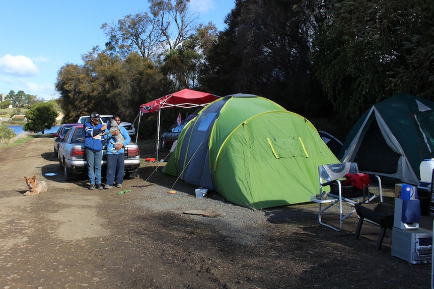 Homeless men stand next to their tents