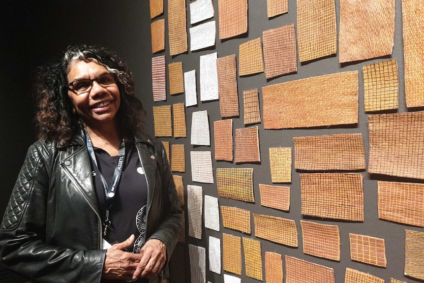 Rosemary Wanganeen stands in front of an artwork