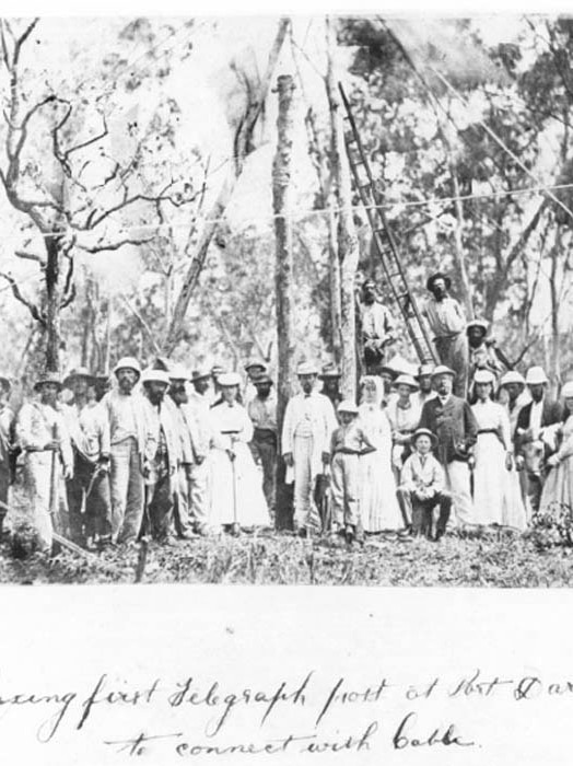A black and white photo shows construction workers standing together in Darwin in 1870.
