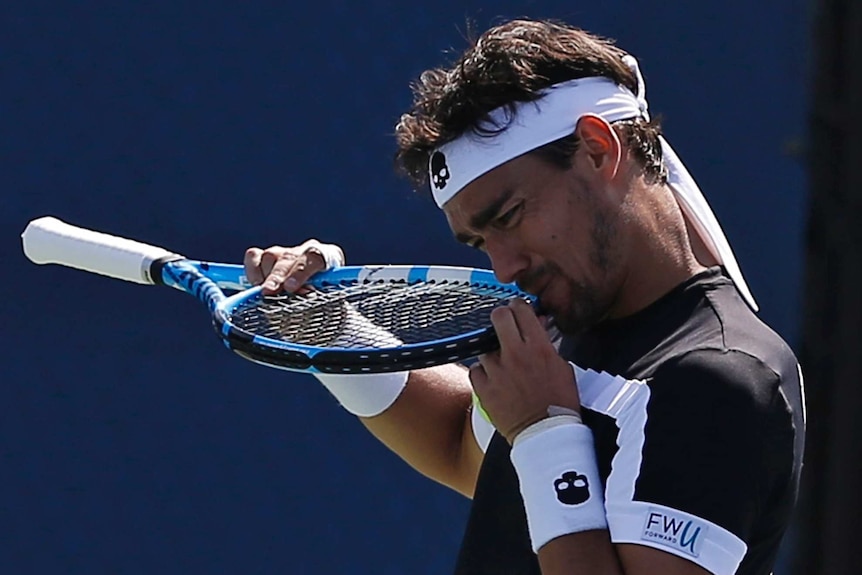 Fabio Fognini bites part of his racquet in frustration after losing a point.